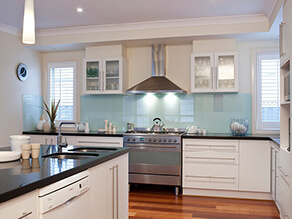 Cream_kitchen_black_polished_countertop_white_cabinets_timber_floorboards_blue_splashback